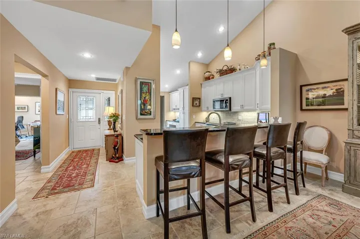 Kitchen with a breakfast bar, dark countertops, stainless steel microwave, and white cabinetry