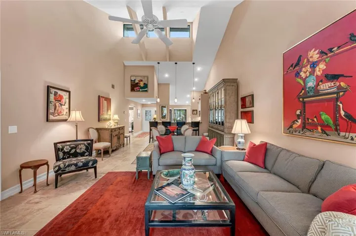Living room featuring a towering ceiling, a ceiling fan, and baseboards