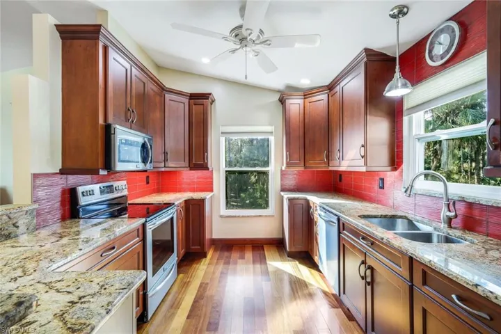 Kitchen featuring sink, hanging light fixtures, light hardwood / wood-style flooring, appliances with stainless steel finishes, and tasteful backsplash
