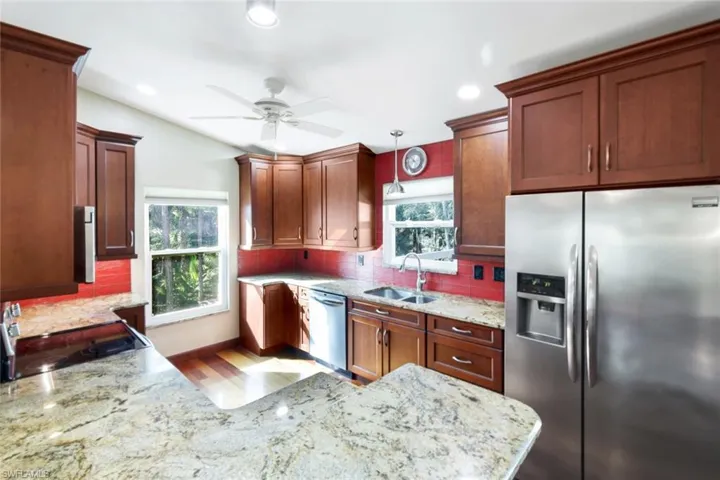 Kitchen with ceiling fan, sink, pendant lighting, decorative backsplash, and appliances with stainless steel finishes