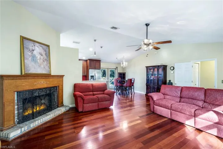 Living room featuring ceiling fan, hardwood / wood-style flooring, and vaulted ceiling