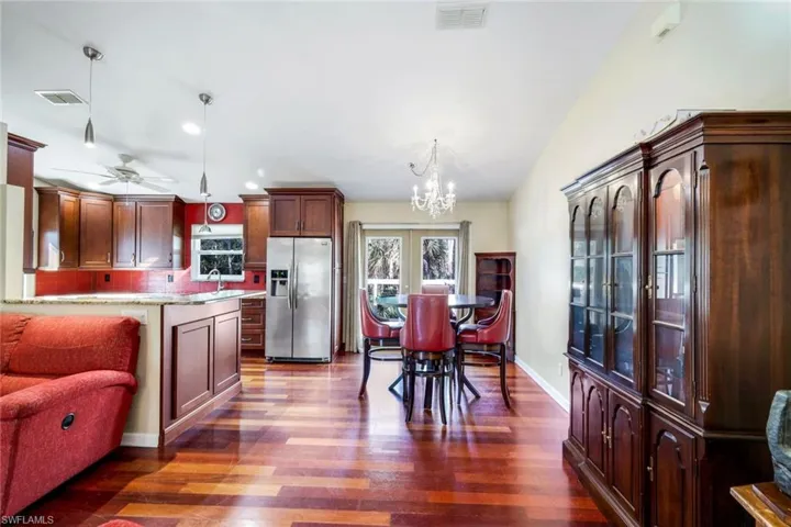 Kitchen featuring ceiling fan with notable chandelier, sink, hardwood / wood-style floors, stainless steel fridge, and decorative light fixtures