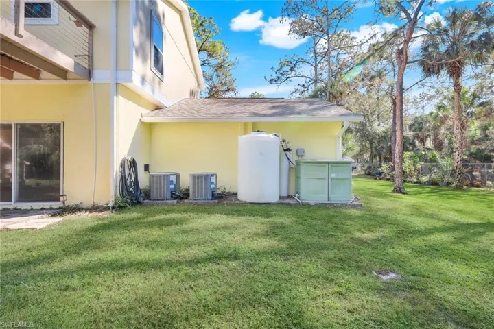 Back of house featuring a yard and central AC
