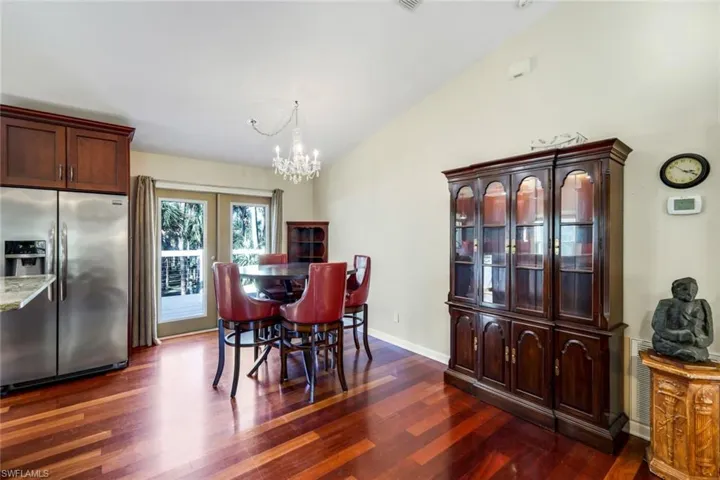 Dining area with hardwood / wood-style flooring, a chandelier, and vaulted ceiling