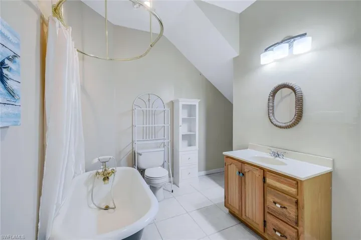 Bathroom featuring toilet, vanity, a tub to relax in, and tile patterned floors