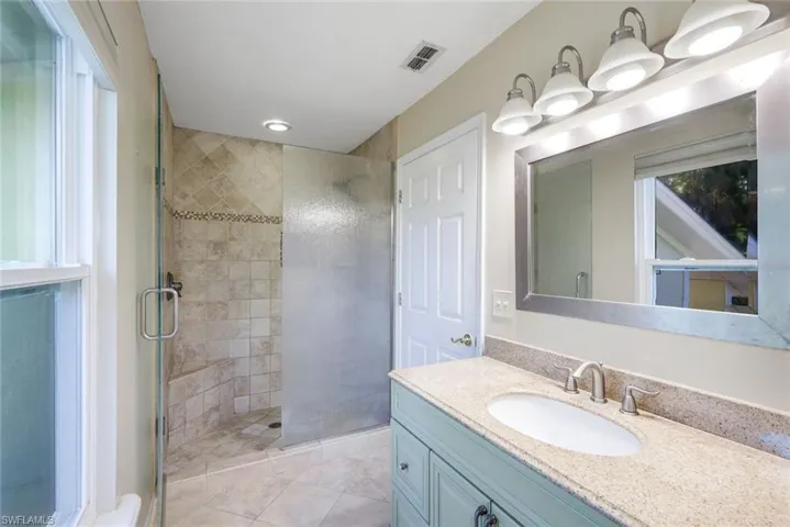 Bathroom featuring tile patterned floors, a shower with door, and vanity