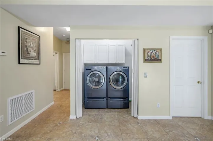 Clothes washing area featuring washer and dryer and cabinets