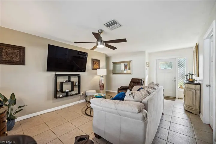 Living area featuring ceiling fan, light tile patterned floors, and baseboards