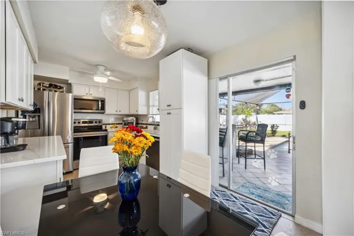 Kitchen with appliances with stainless steel finishes, white cabinets, light countertops, and a ceiling fan