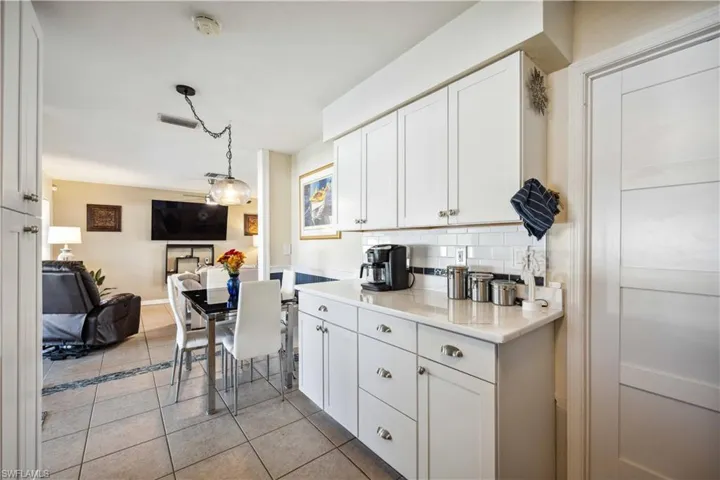 Kitchen with light tile patterned flooring, white cabinetry, open floor plan, decorative backsplash, and pendant lighting