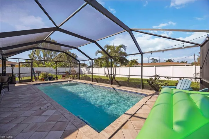 View of swimming pool featuring a patio area, a fenced backyard, and glass enclosure