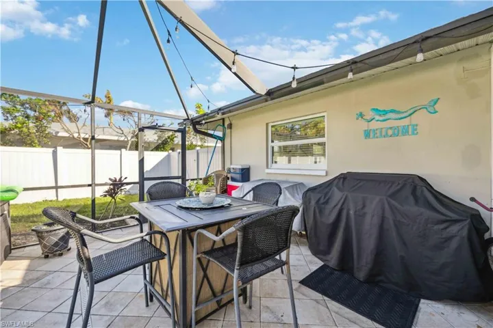 View of patio with fence, outdoor dining space, and glass enclosure