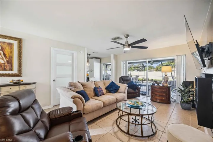 Living room with a ceiling fan and light tile patterned floors