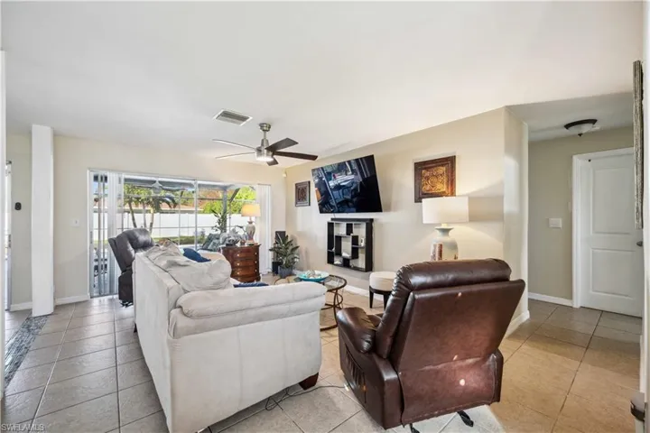 Living area featuring ceiling fan, light tile patterned flooring, and baseboards