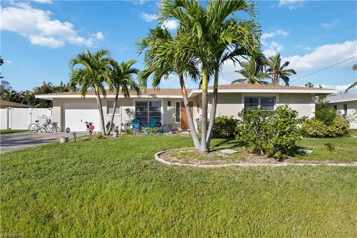 Single story home featuring a garage, stucco siding, driveway, and a gate