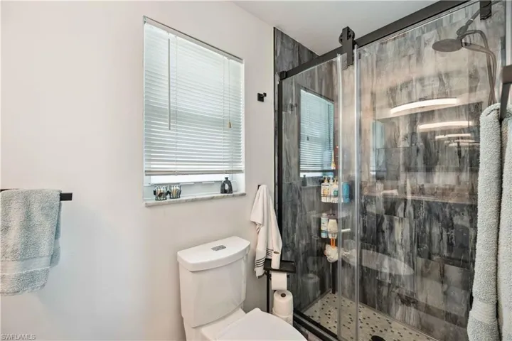Full bath featuring toilet and a stall shower