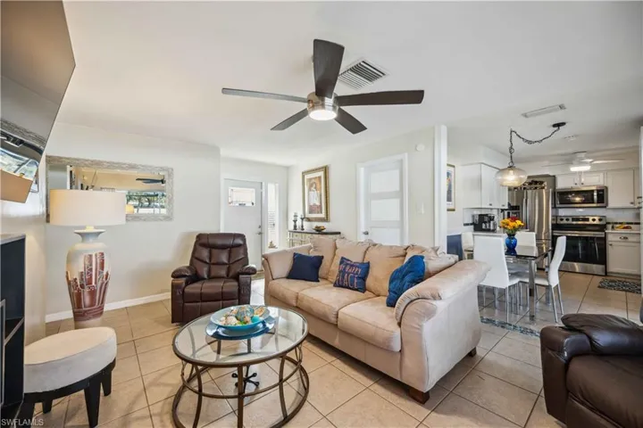Living room with ceiling fan, light tile patterned floors, and baseboards