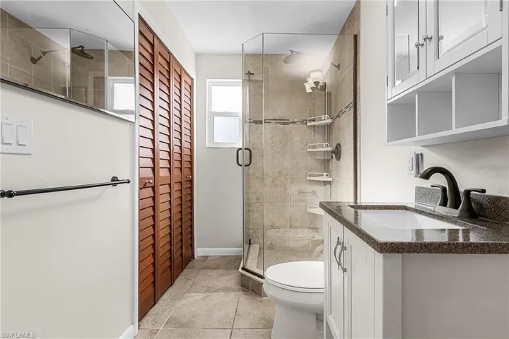 Bathroom featuring a closet, vanity, a shower stall, and light tile patterned flooring