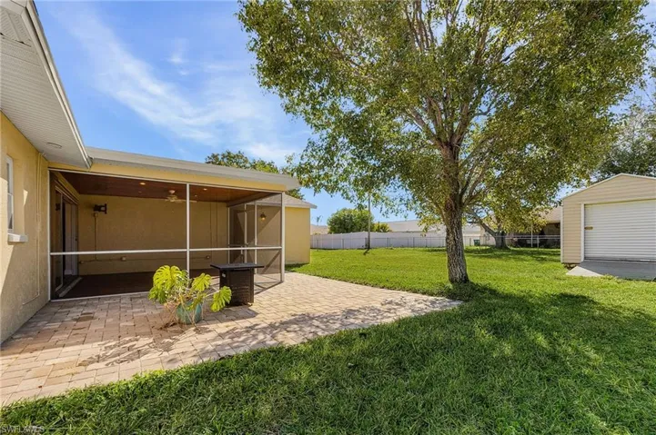 Fenced backyard featuring a sunroom, an outbuilding, and a patio area