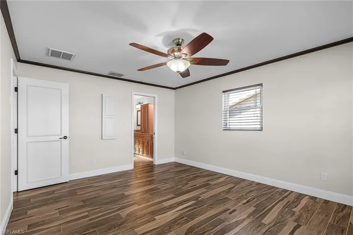 Unfurnished bedroom featuring crown molding, wood finish floors, ceiling fan, and connected bathroom
