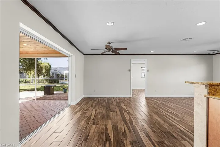 Empty room featuring ceiling fan, crown molding, dark wood finished floors, and recessed lighting