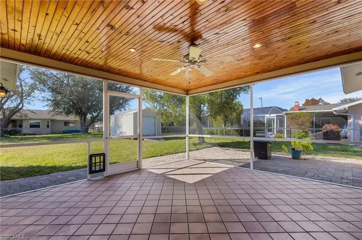 Unfurnished sunroom with a ceiling fan and a patio area