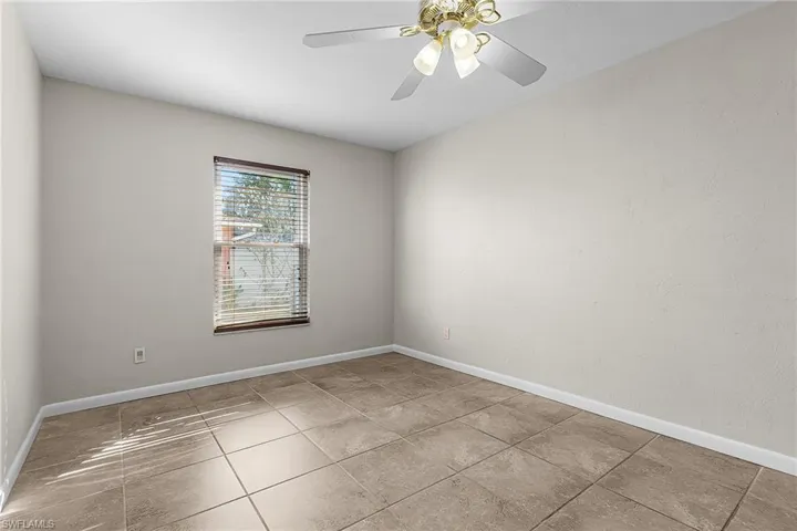 Empty room with ceiling fan and light tile patterned floors