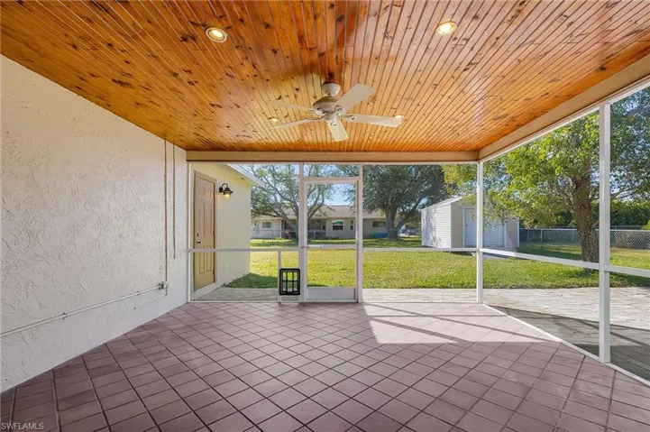 Unfurnished sunroom with a ceiling fan and a patio