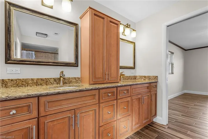 Full bath with double vanity, crown molding, a shower with curtain, and wood tiled floors