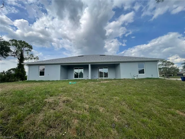 Rear view of house with stucco siding and a lawn