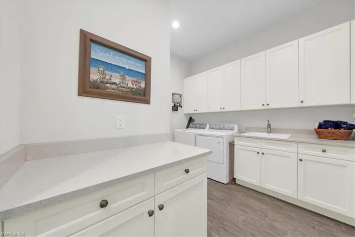 Laundry room featuring cabinet space, washing machine and dryer, wood finish floors, and recessed lighting