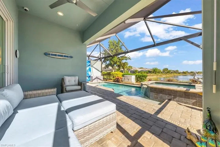 View of patio / terrace with a sunroom, glass enclosure, a ceiling fan, a pool with connected hot tub, and a water view