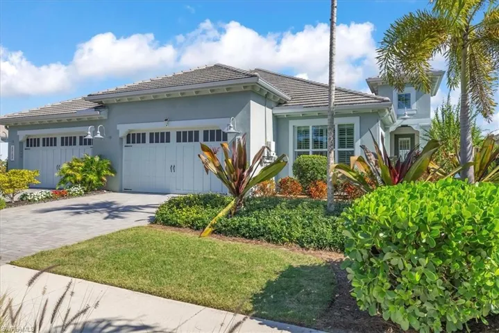 View of front facade featuring a garage, decorative driveway, stucco siding, and a tiled roof