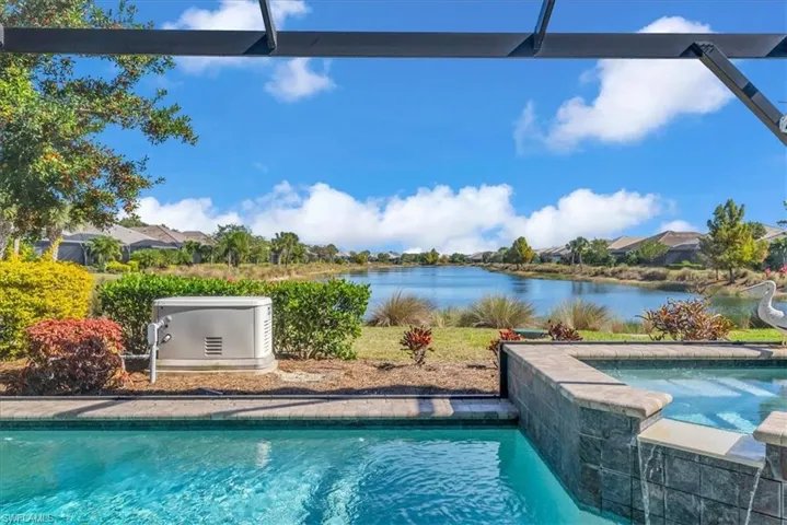 View of swimming pool with a water view, a patio, and a pool with connected hot tub