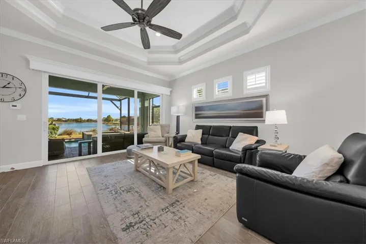 Living area featuring a water view, ornamental molding, wood finished floors, a raised ceiling, and a sunroom