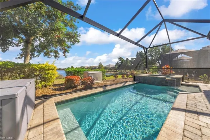 View of swimming pool featuring a lanai, a sunroom, a pool with connected hot tub, and a patio