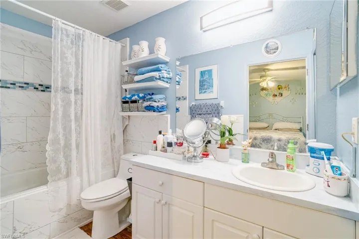 Full bathroom featuring visible vents, connected bathroom, toilet, vanity, and shower / bathtub combination with curtain