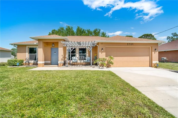 View of front of house featuring stucco siding, driveway, a front lawn, and a garage