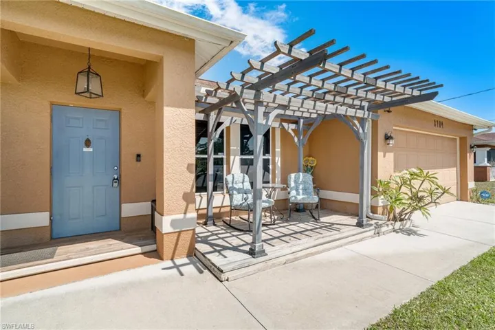 View of exterior entry featuring stucco siding, a pergola, and a garage