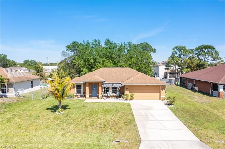 Ranch-style home with fence, an attached garage, stucco siding, a front lawn, and concrete driveway