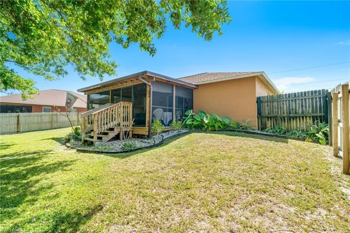 Rear view of house featuring stucco siding, a lawn, a fenced backyard, and a sunroom