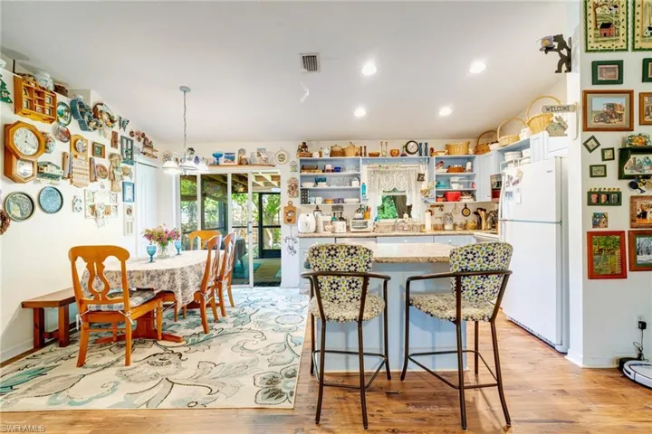 Kitchen with open shelves, light wood-style flooring, freestanding refrigerator, light countertops, and a center island