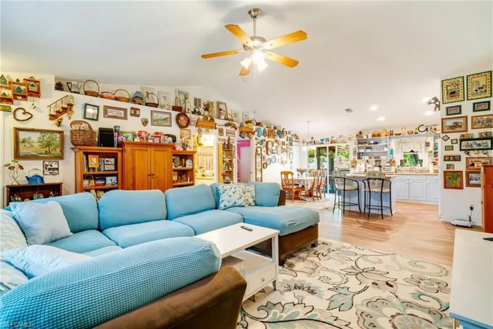 Living room featuring lofted ceiling, ceiling fan, and light wood finished floors