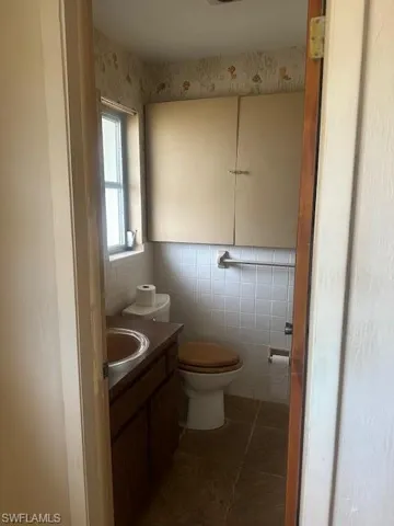 Master Bathroom featuring tile walls, vanity, tile patterned flooring, and toilet
