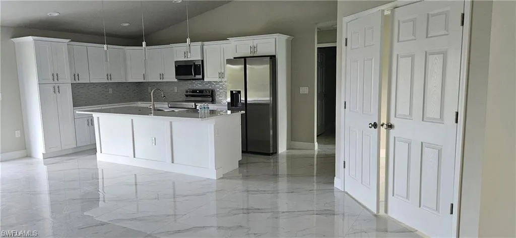 Kitchen featuring decorative light fixtures, sink, white cabinetry, and stainless steel appliances