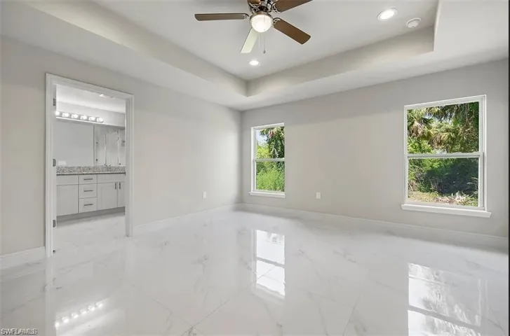 Unfurnished room featuring a raised ceiling and ceiling fan