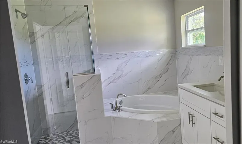Bathroom featuring separate shower and tub and vanity