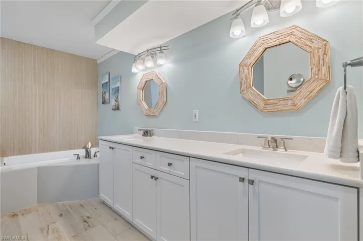Bathroom featuring dual vanity, a washtub, and crown molding