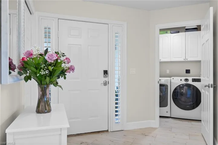 Washroom featuring light wood-type flooring, cabinets, and washer and clothes dryer