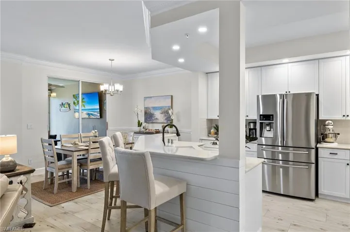 Kitchen with decorative light fixtures, white cabinetry, stainless steel fridge with ice dispenser, and tasteful backsplash
